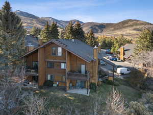 Back of property featuring a chimney, a deck with mountain view, and a yard