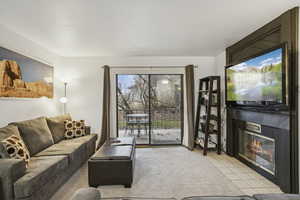 Living room featuring light tile patterned floors and a glass covered fireplace