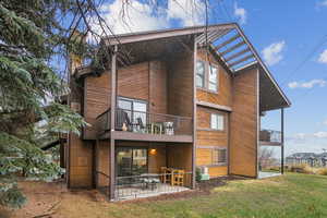 Back of property with a patio area, a balcony, and a lawn