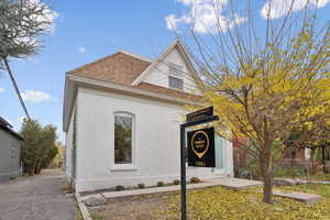 View of front facade featuring roof with shingles and stucco siding