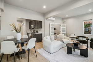 Living area with light wood-style floors, recessed lighting, and a wall mounted air conditioner