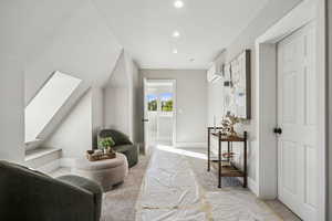 Living area featuring light colored carpet, a skylight, and recessed lighting