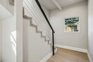 Staircase featuring wood finished floors and beam ceiling