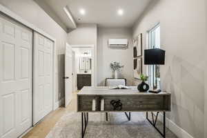 Office with light wood-style flooring and a wall mounted air conditioner