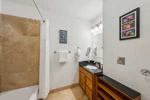 Full bath featuring shower / tub combo with curtain, vanity, and light tile patterned floors