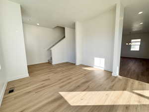 Unfurnished living room featuring light wood-style flooring, recessed lighting, stairway, and a textured ceiling