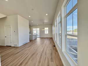 Unfurnished living room featuring a chandelier, light wood-style floors, and recessed lighting