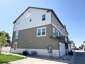 View of property exterior with driveway, an attached garage, stucco siding, and brick siding