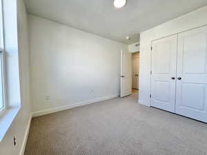 Unfurnished bedroom with carpet, a textured ceiling, and a closet