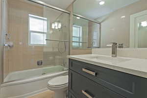 Full bathroom featuring vanity, shower / bath combination with glass door, light tile patterned floors, and tile walls
