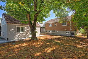 Rear view of property featuring a patio, a lawn, stucco siding, and brick siding