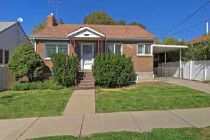 Bungalow featuring brick siding, driveway, a carport, a gate, and a chimney