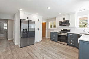 Kitchen with white cabinetry, stainless steel appliances, healthy amount of natural light, recessed lighting, and light stone counters