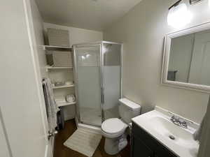 Bathroom with vanity, a shower stall, dark wood-type flooring, and a textured ceiling