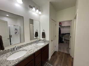 Master Bathroom with double vanity, dark wood-type flooring, a stall shower, and a spacious closet