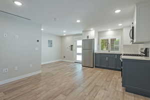 Kitchen with white cabinetry, plenty of natural light, stainless steel appliances, light wood-type flooring, and recessed lighting