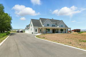 View of front facade with covered porch, a garage, roof with shingles, and driveway