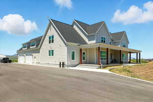 View of front of house featuring a porch, roof with shingles, and driveway