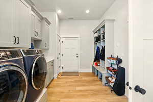 Laundry room with light wood-style flooring, cabinet space, independent washer and dryer, and recessed lighting