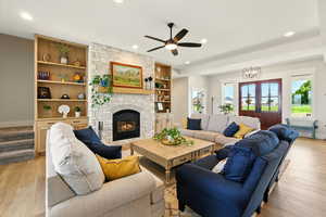 Living room featuring light wood-style floors, stairs, a fireplace, recessed lighting, and a ceiling fan