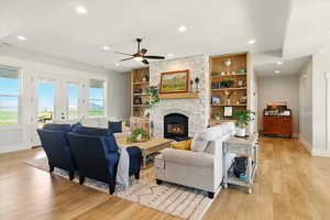Living area featuring recessed lighting, light wood-style floors, a fireplace, a ceiling fan, and french doors
