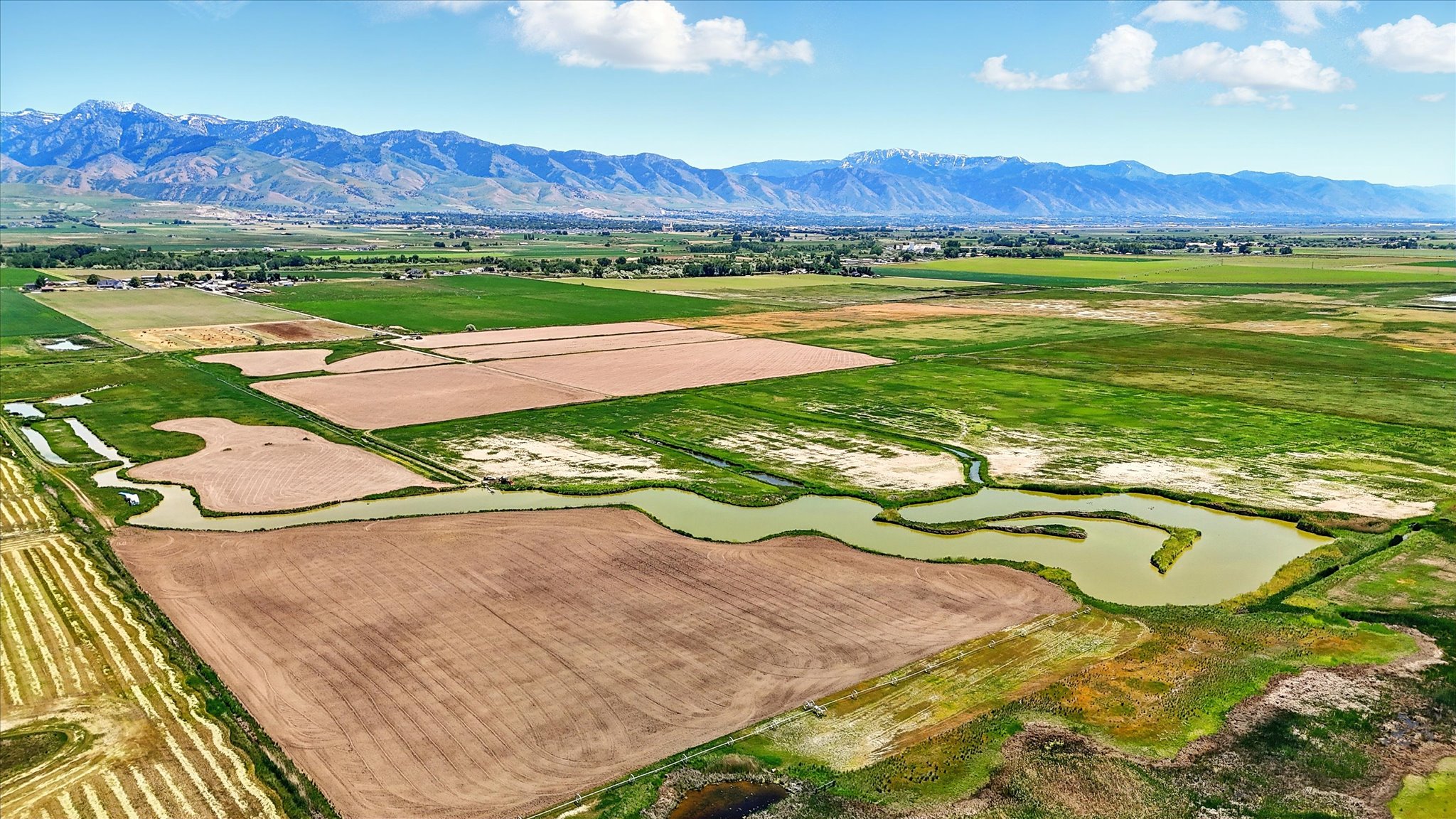 View of rural area featuring extensive farmland and a mountain backdrop and water