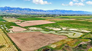 View of rural area featuring extensive farmland and a mountain backdrop and water
