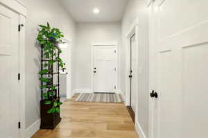 Hallway with light wood-style floors and recessed lighting