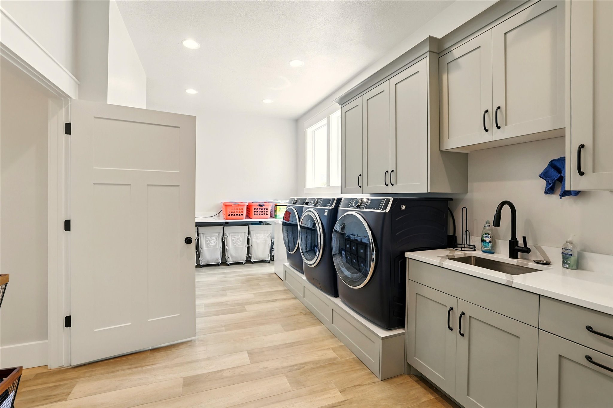 Laundry room with light wood-style flooring, cabinet space, recessed lighting, and washing machine and clothes dryer
