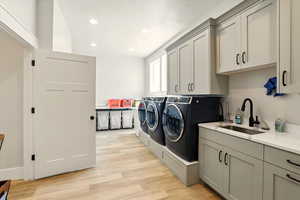 Laundry room with light wood-style flooring, cabinet space, recessed lighting, and washing machine and clothes dryer