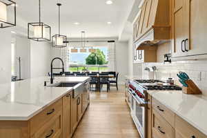 Kitchen featuring stainless steel appliances, hanging light fixtures, light stone counters, recessed lighting, and light wood-style floors
