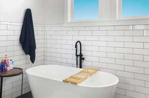 Full bathroom featuring tile walls and a freestanding bath