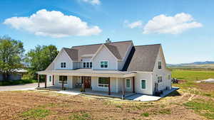 View of front of home with a shingled roof, covered porch, a standing seam roof, a metal roof, and a chimney