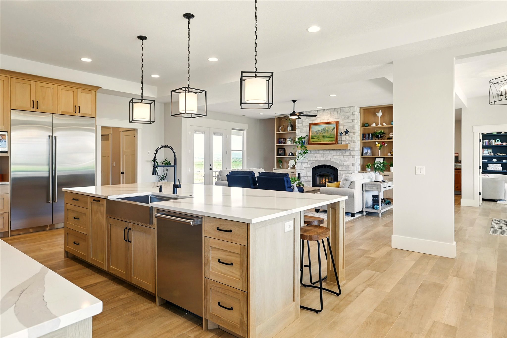 Kitchen featuring appliances with stainless steel finishes, a fireplace, pendant lighting, a large island with sink, and recessed lighting
