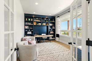 Home office with french doors, light wood-type flooring, recessed lighting, and built in features