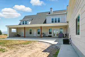Back of property featuring french doors, a chimney, a porch, roof with shingles, and a patio