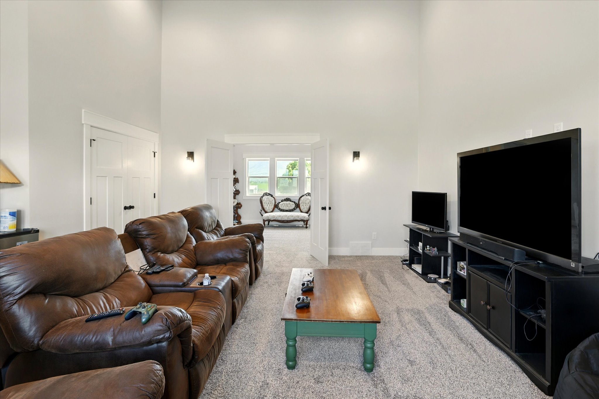 Media room with carpet and a towering ceiling