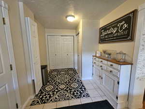 Hallway featuring a textured ceiling and light tile patterned floors