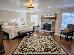 Bedroom with a textured ceiling, ornamental molding, a fireplace, dark wood-type flooring, and recessed lighting