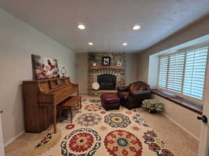Carpeted living room featuring a fireplace, a textured ceiling, and recessed lighting