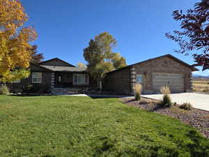 Ranch-style home featuring brick siding, driveway, a front yard, and a garage