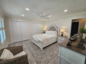 Bedroom featuring crown molding, multiple closets, wood finished floors, recessed lighting, and ceiling fan