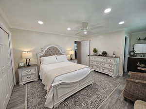 Bedroom featuring crown molding, a closet, dark wood-type flooring, recessed lighting, and a ceiling fan