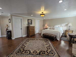 Bedroom featuring a textured ceiling, recessed lighting, dark wood-style flooring, and ornamental molding