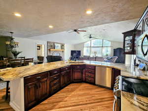 Kitchen featuring open floor plan, appliances with stainless steel finishes, light wood-type flooring, light countertops, and a textured ceiling