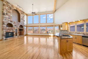 Kitchen featuring decorative backsplash, open floor plan, dark stone counters, light wood-style flooring, and a kitchen breakfast bar