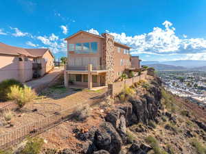 Back of property with a fenced backyard, a sunroom, a patio area, stucco siding, and a mountain view