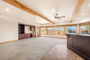 Unfurnished living room featuring beam ceiling, light carpet, recessed lighting, light tile patterned floors, and ceiling fan