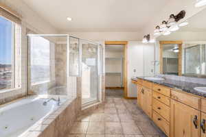 Full bath with double vanity, a walk in closet, a tub with jets, light tile patterned floors, and a shower stall