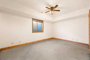 Spare room with light colored carpet, ceiling fan, and a tray ceiling